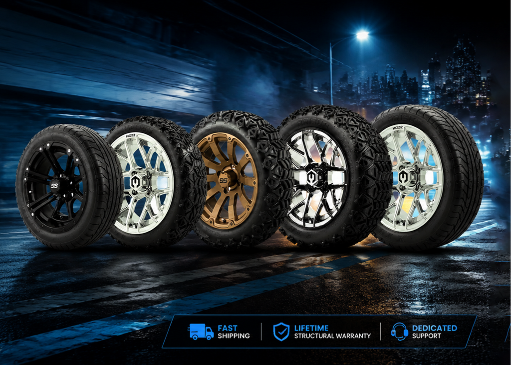 Four off-road tires mounted on multi-spoke wheels, shown from a low angle on a wet dark road with motion blur and city lights in the background. Blue and white feature badges appear at the bottom right.